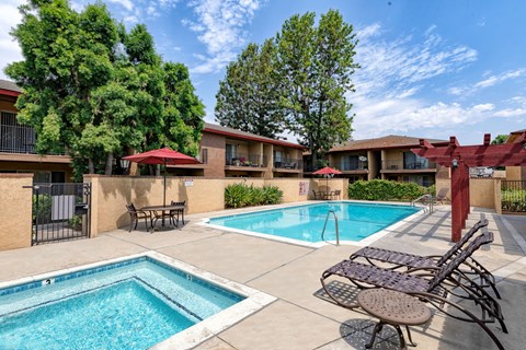 A pool area with a small pool and a larger pool with chairs around it.