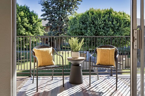 Two chairs with yellow pillows sit on a patio.