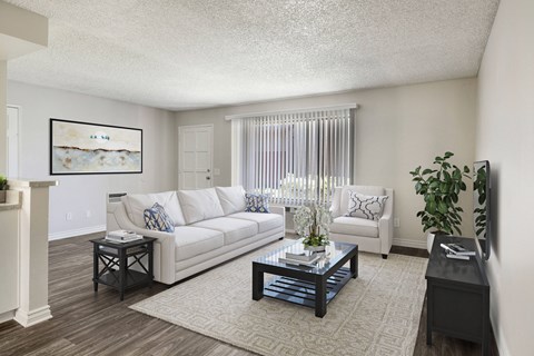 A living room with a white couch, a coffee table, and a painting on the wall.