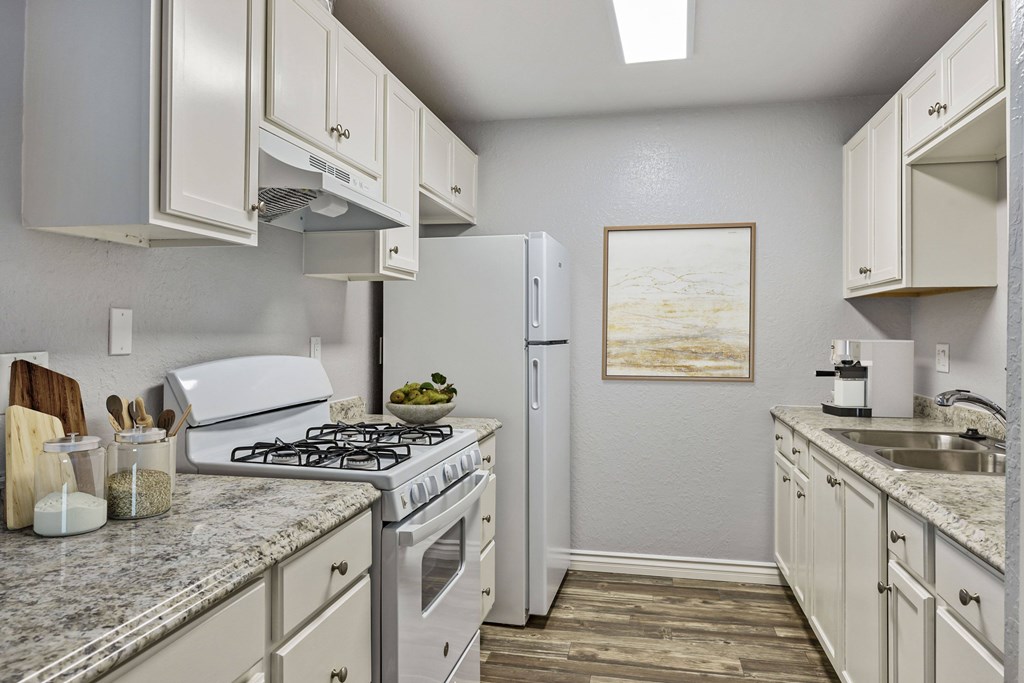 A kitchen with a white stove top oven and a white refrigerator.