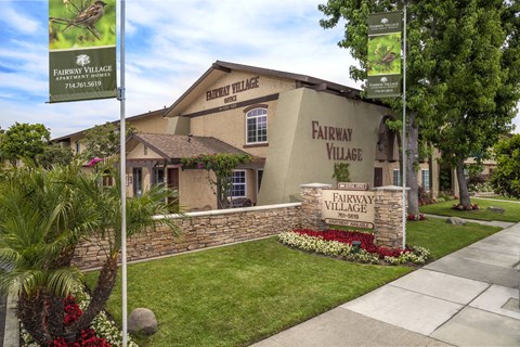The front of Fairway Village with a sign and flowers.