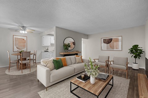 A living room with a white couch, wooden coffee table, and a dining table with chairs.