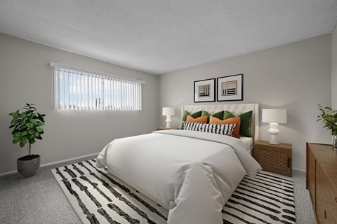 A bedroom with a large bed, a potted plant, and a striped rug.