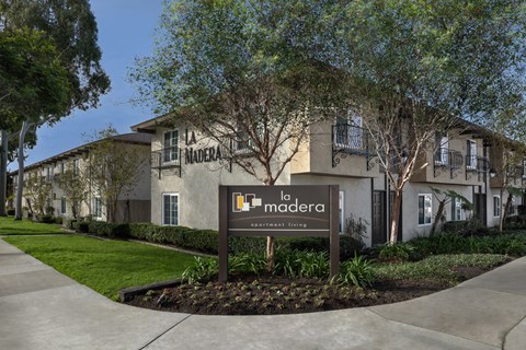 A sign for a community named La Madera stands in front of a building.