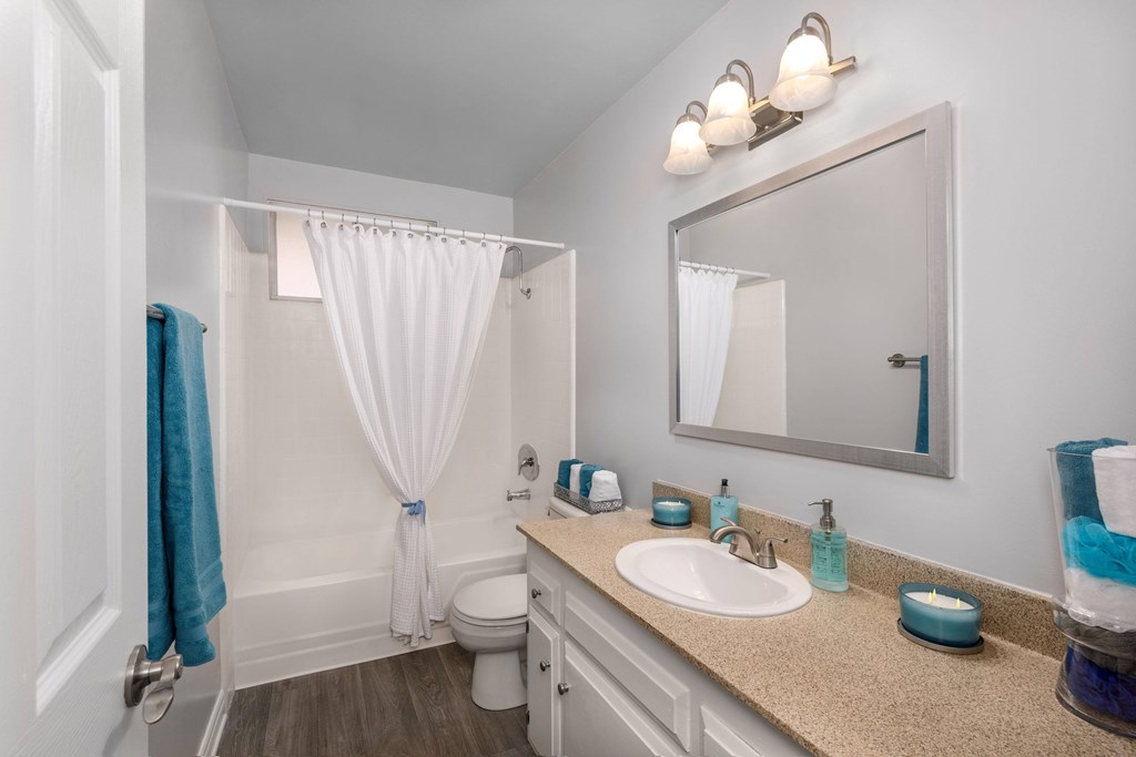 A bathroom with a toilet, sink, mirror, and a blue towel.