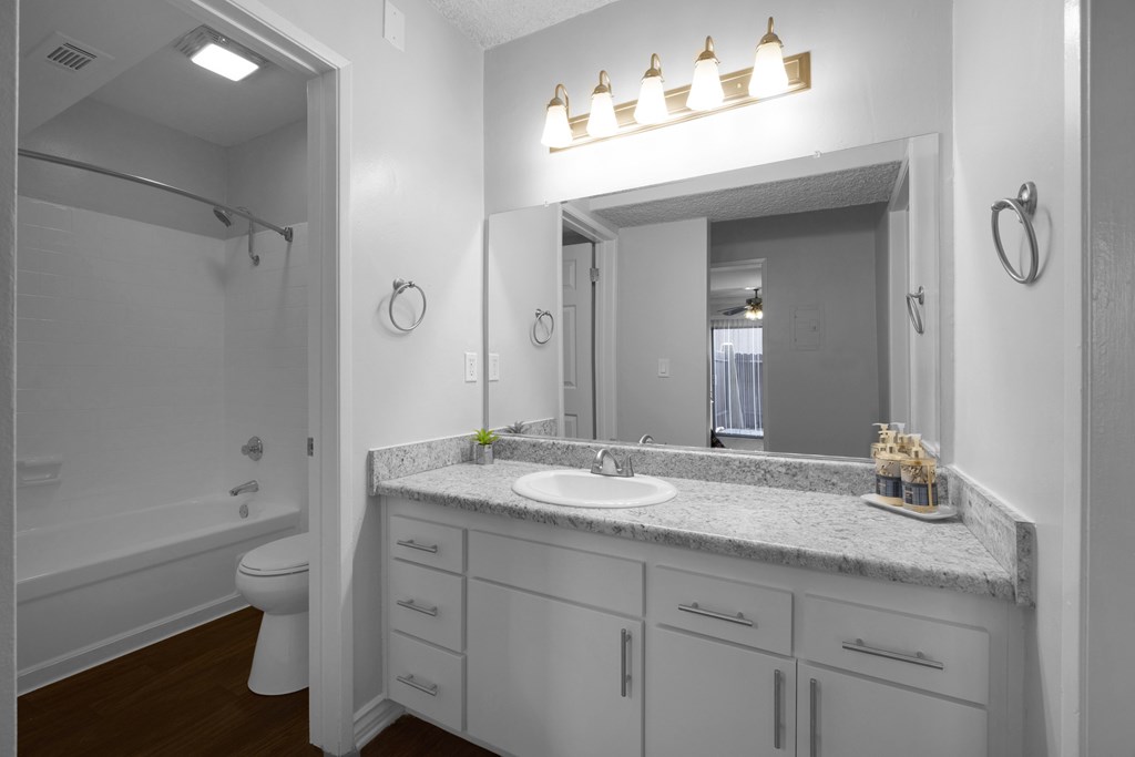 A bathroom with a marble countertop and a white sink.