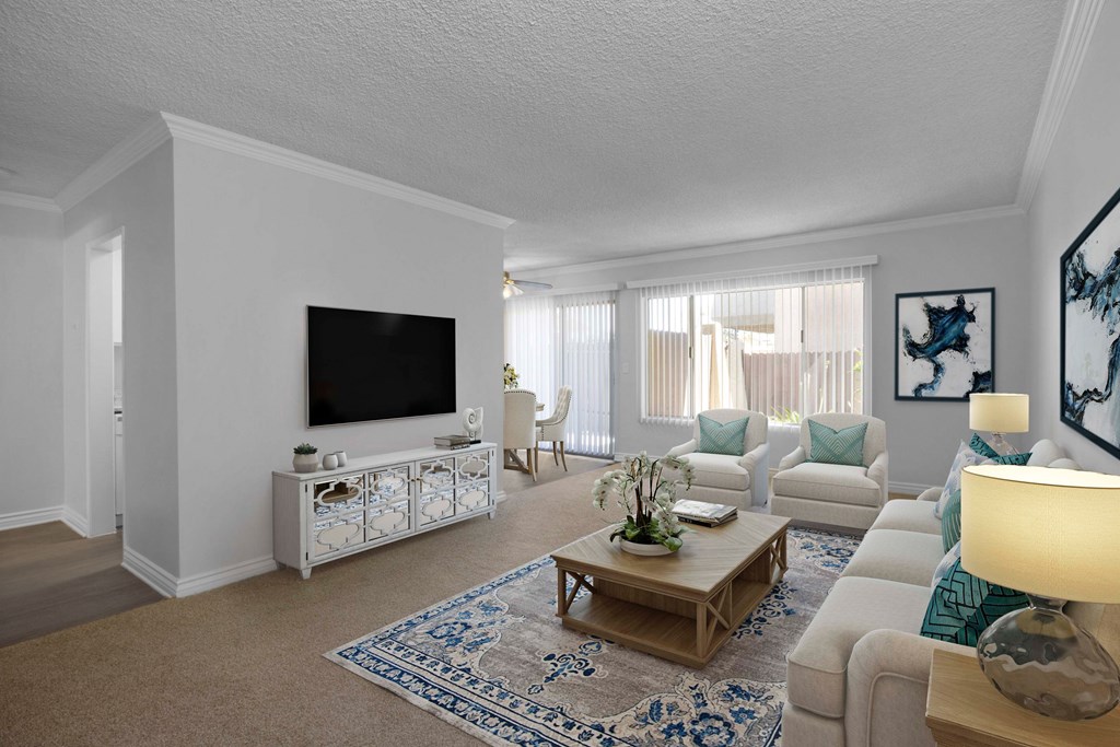 A living room with a white couch, a coffee table, and a television.