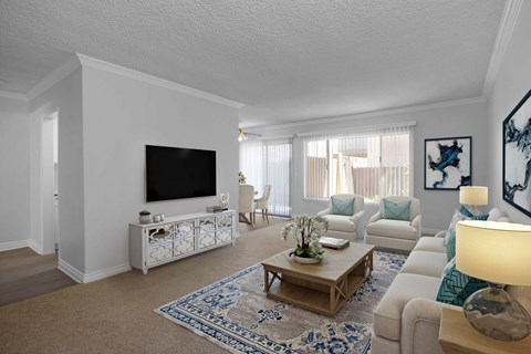 A living room with a white couch, a coffee table, and a television.
