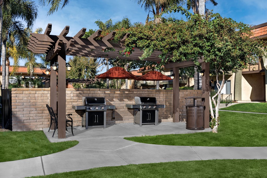 A patio with a grill and a pergola.