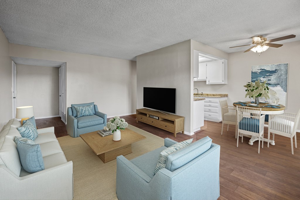 A living room with a white couch, blue armchair, and a wooden coffee table.