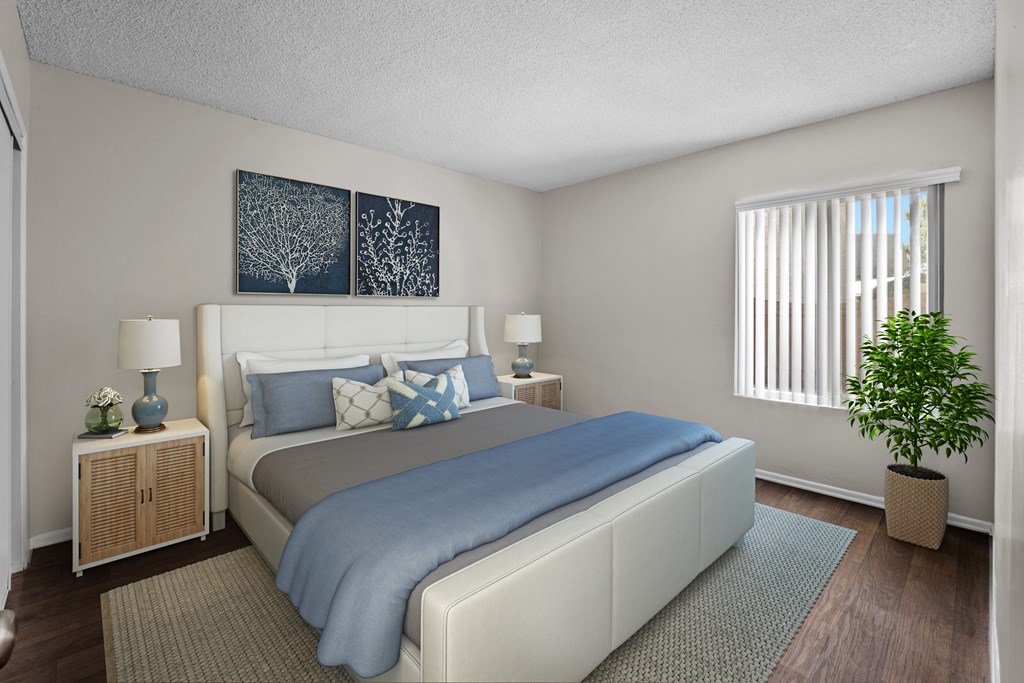 A bedroom with a bed, nightstands, and a plant.