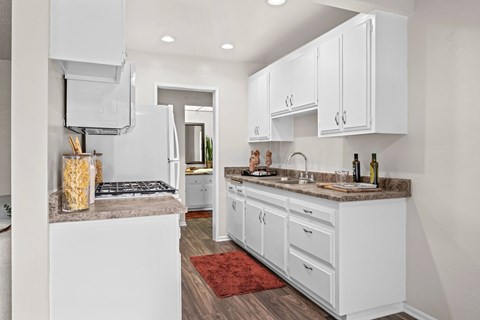 A kitchen with white cabinets and a red rug on the floor.
