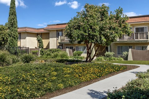 A building with a yellow flower bed in front of it.