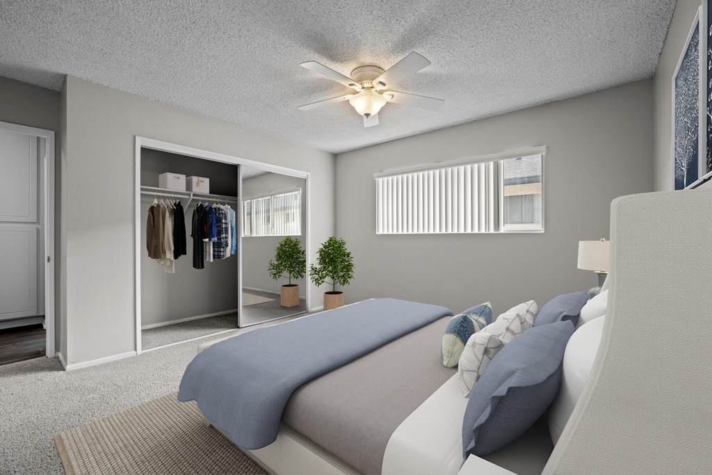 A bedroom with a bed, pillows, a ceiling fan, and a closet.