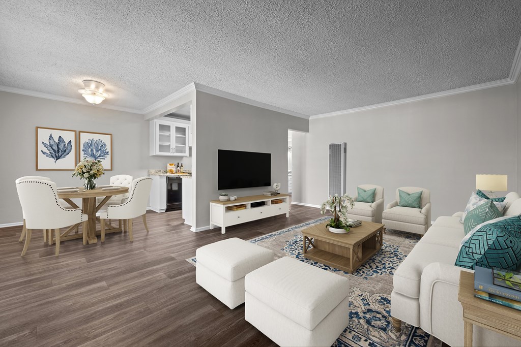A living room with a white couch, a wooden coffee table, and a television.
