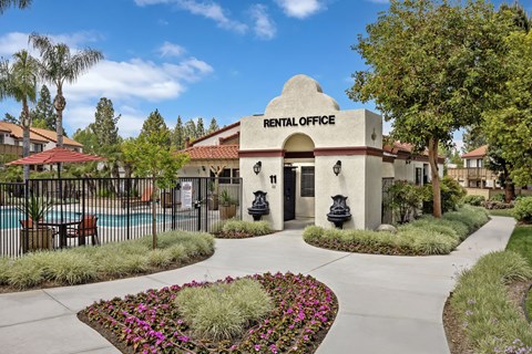 A rental office is surrounded by flowers and a pool.