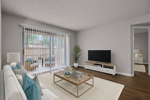 A living room with a white couch, a wooden coffee table, and a flat screen TV.