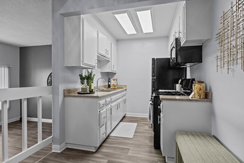 A modern kitchen with white cabinets and a black refrigerator.