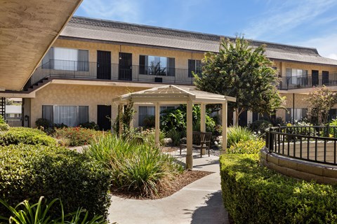 A building with a balcony and a gazebo in the front yard.