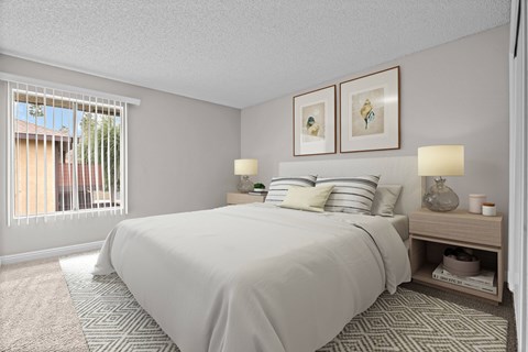 A bedroom with a large bed and a window with blinds.