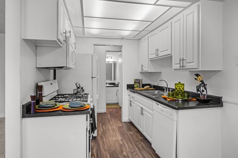 A kitchen with white cabinets and a black countertop.