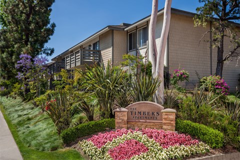 A sign that says "The Timbers Apartments" is in front of a building.