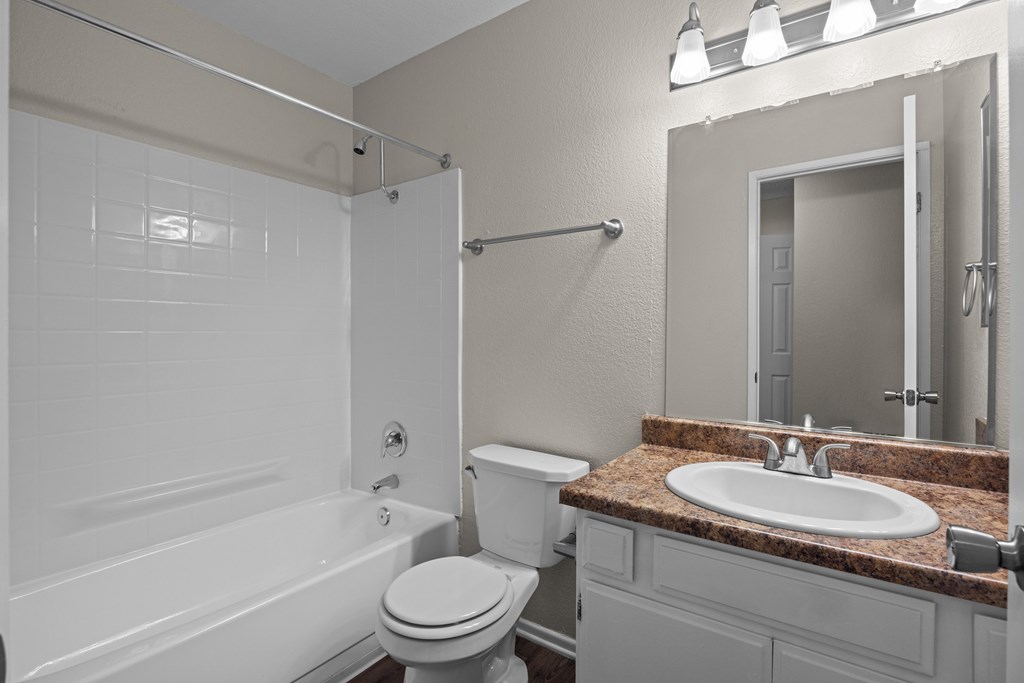 A white bathroom with a toilet, sink, and shower.
