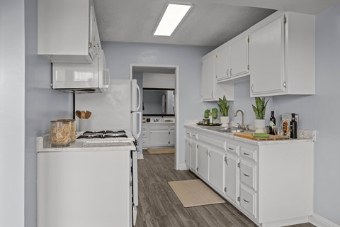 A white kitchen with a stove, oven, and cabinets.