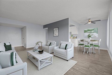 A living room with white furniture and a ceiling fan.