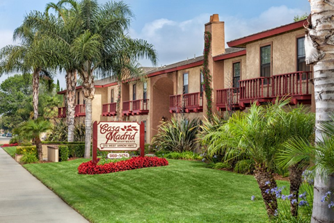 A sign for Casa Madrid sits in front of a building with red balconies.