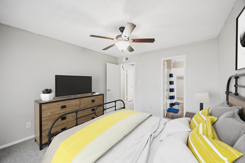 A bedroom with a bed, a dresser, and a ceiling fan.