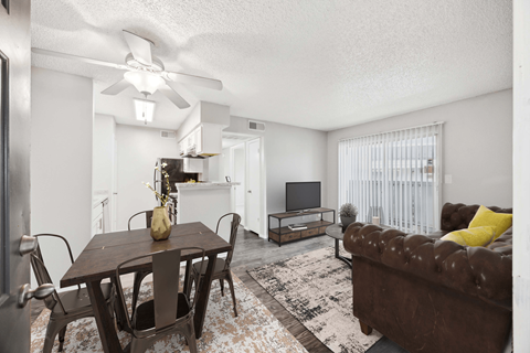 A living room with a brown couch, a wooden table, and a ceiling fan.