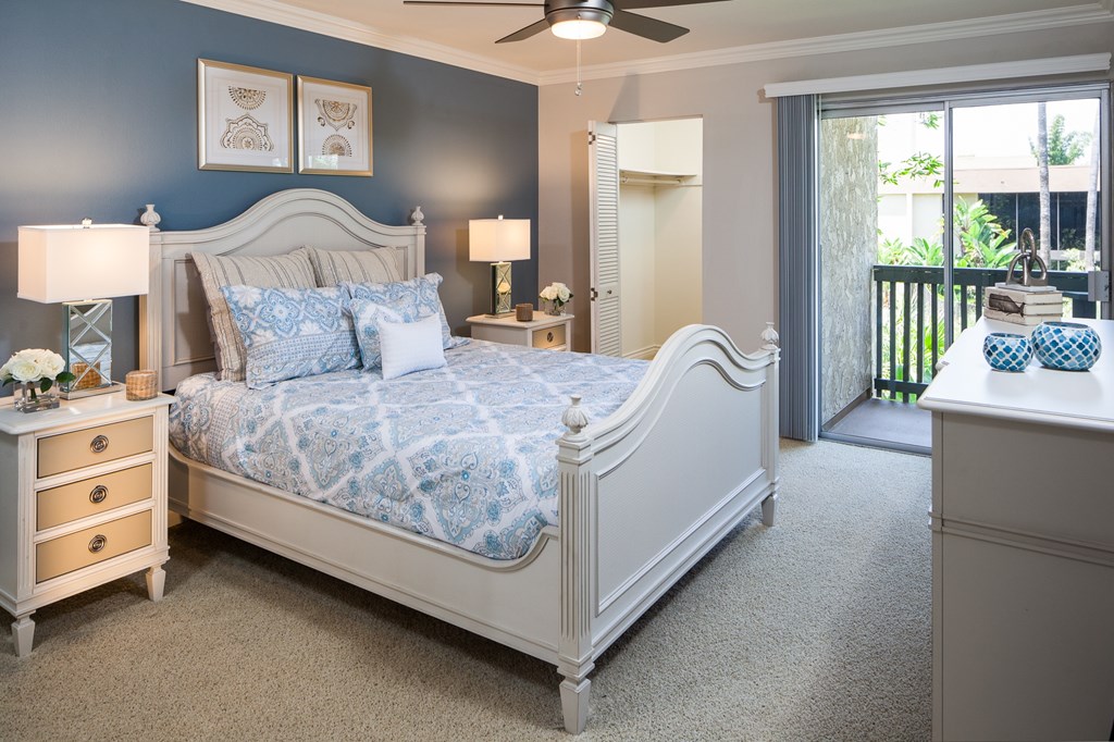 A bedroom with a large bed, a dresser, and a ceiling fan.