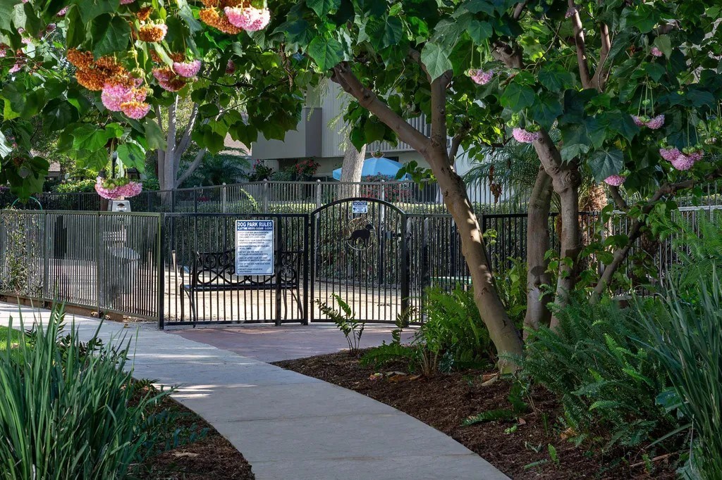 A pathway with a sign and a fence in the background.