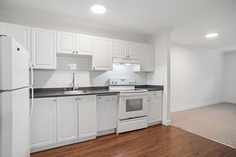 A kitchen with white cabinets and appliances.