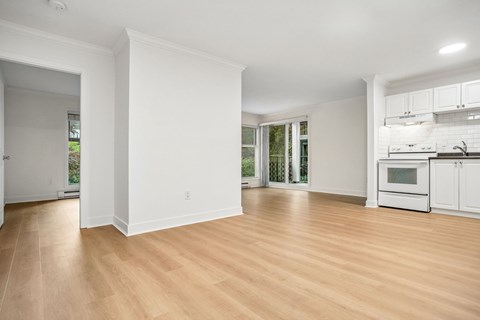 A spacious room with wooden flooring and white walls.