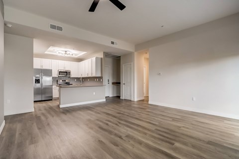 A spacious kitchen and living room with wood flooring and white walls.