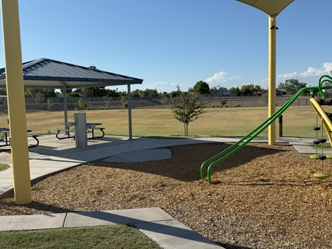 A playground with a green slide and a yellow pole.