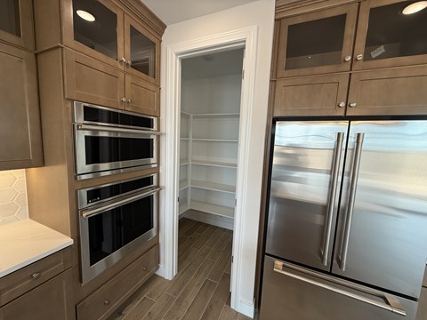 A kitchen with wooden cabinets and a stainless steel refrigerator.