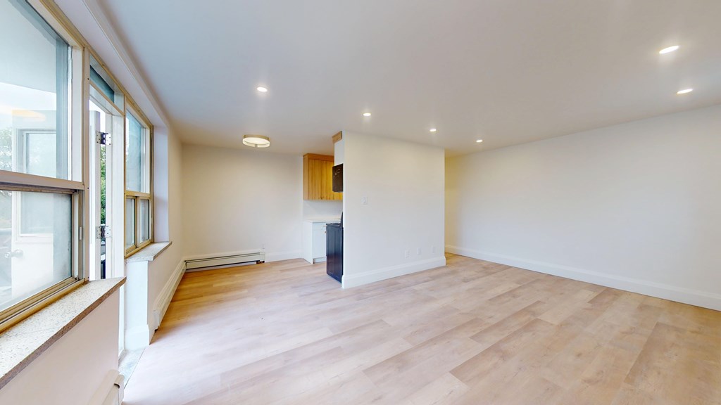 A room with wooden flooring and a window on the left side.