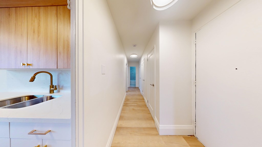 A long hallway with white walls and a wooden floor.