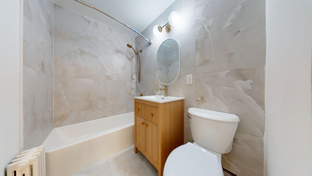 A white toilet sits next to a wooden cabinet in a bathroom.