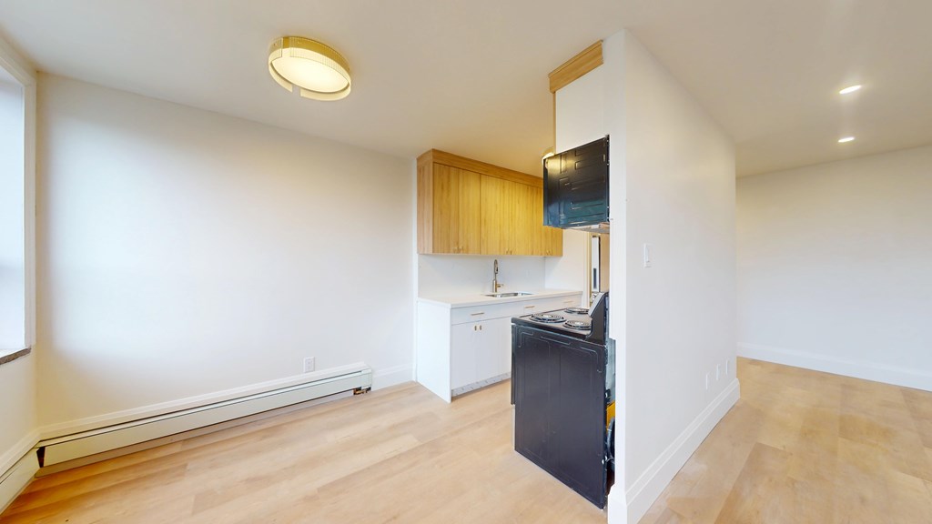 A kitchen area with a black fridge and wooden cabinets.