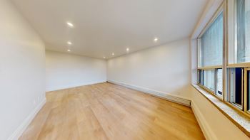 A room with wooden floors and a window on the right side.