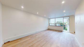 A large empty room with wooden floors and a window.