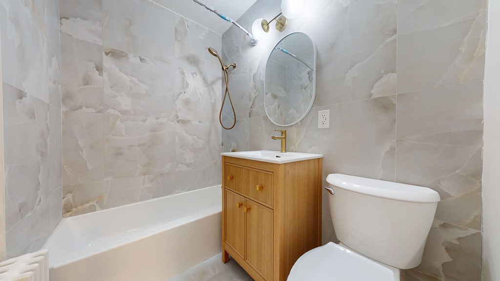 A white toilet sits next to a white bathtub in a bathroom.