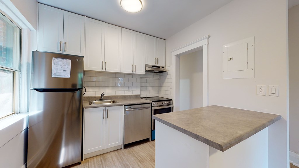A kitchen with a stainless steel refrigerator and white cabinets.