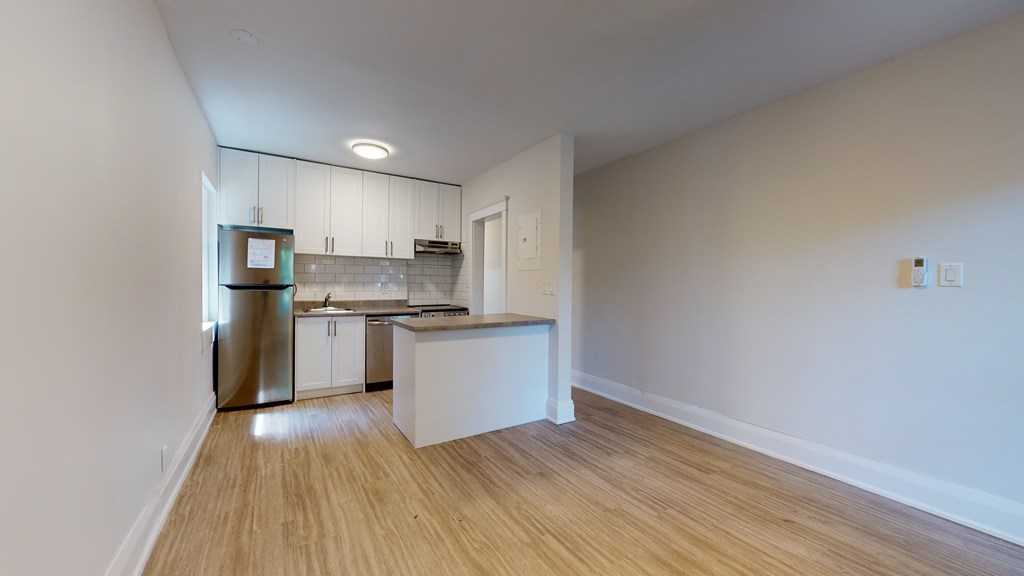 A kitchen with white cabinets and a wooden floor.