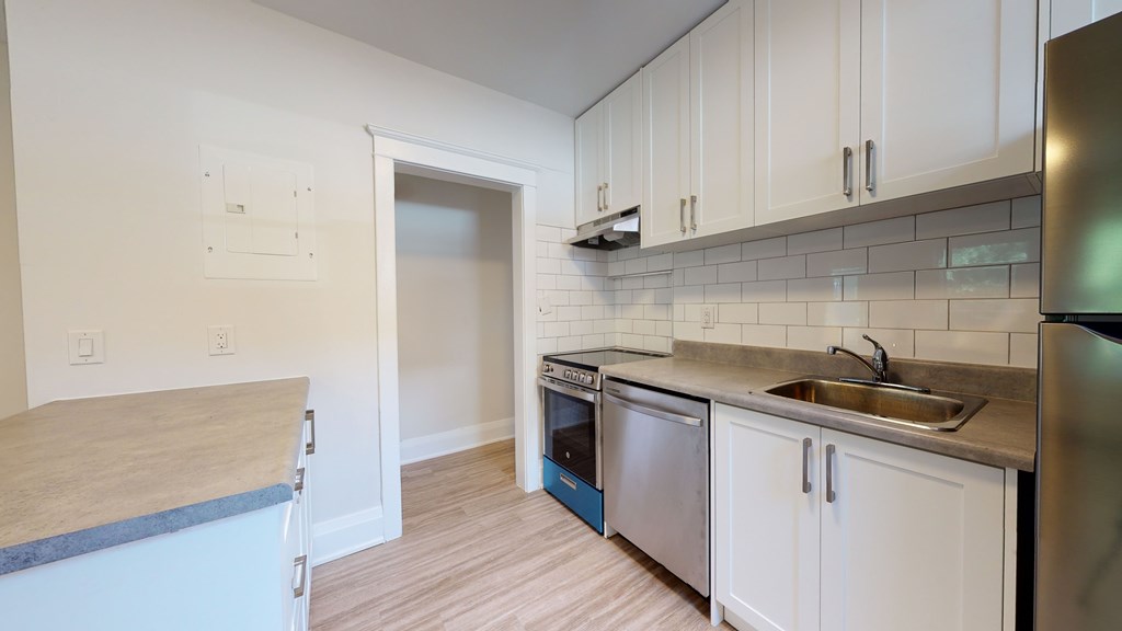 A kitchen with white cabinets and a stainless steel refrigerator.