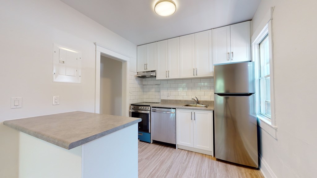A kitchen with white cabinets and a stainless steel refrigerator.